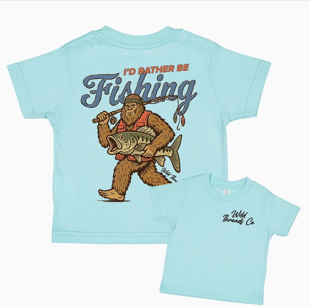 Light blue t-shirt with a graphic of BigFoot holding a fish and text 'I'd Rather Be Fishing' 